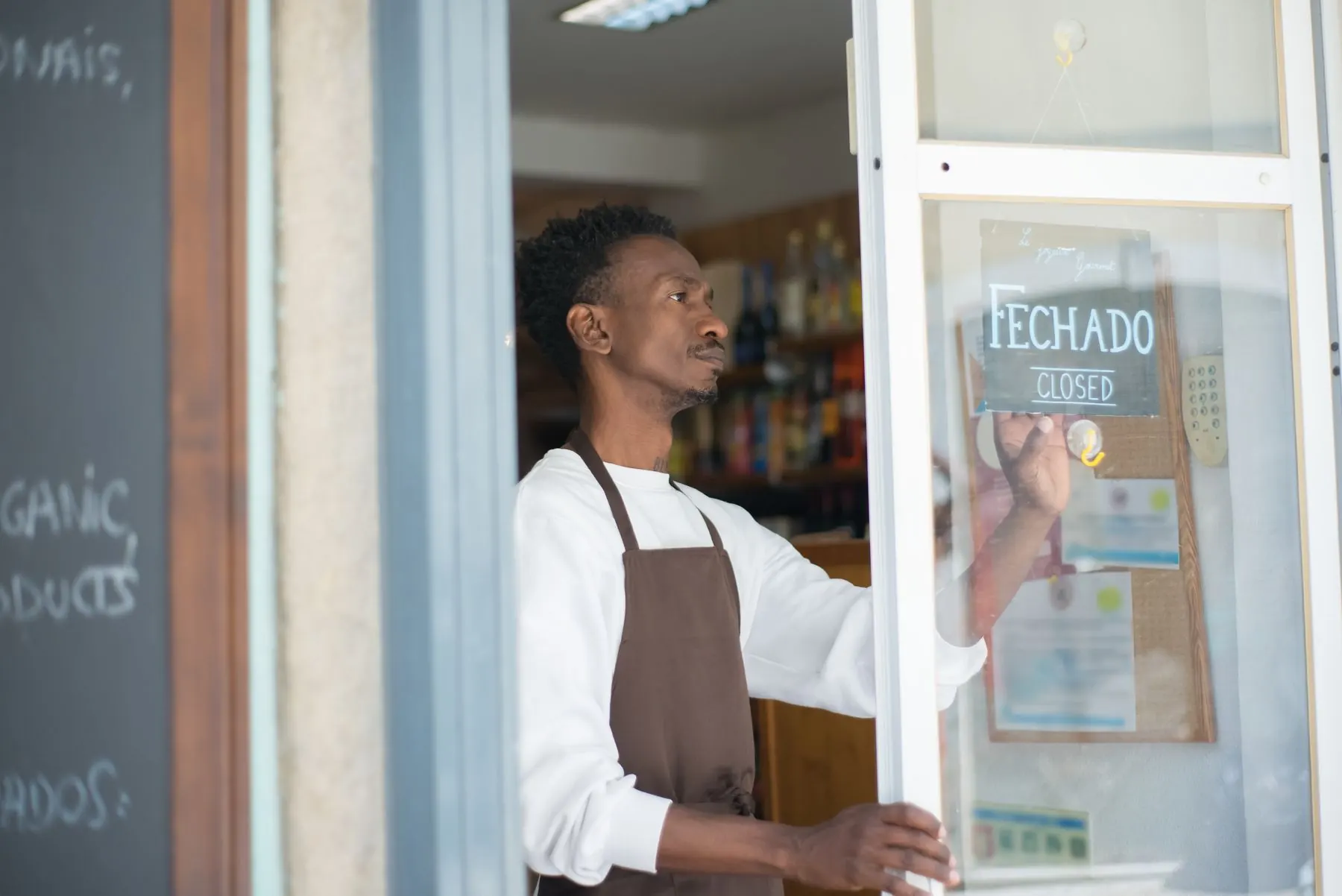 Dueño de una tienda girando el cartel de cerrado en la puerta